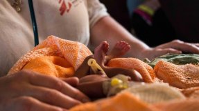 Ett nyfött barn insvept i en filt ligger framför en anställd på en klinik i Sydsudan