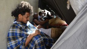 Flyktingar sitter utomhus i förvaret i Zintan, Libyen