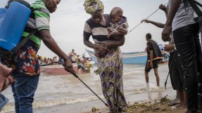 Sanitetsarbetare desinfekterar händer och fötter på en kvinna i vattenbrynet för att motverka kolera.
