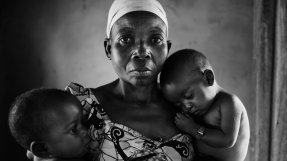 Svartvitt foto av en kvinna hållandes ett litet barn på varje arm.