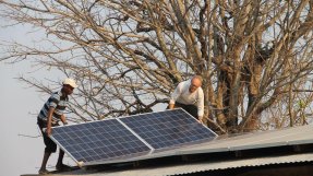 Två män installerar en solpanel på ett tak