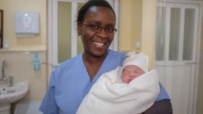 En sjuksköterska håller ett nyfött barn