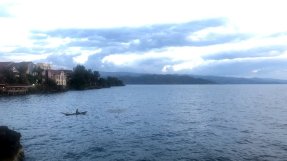 Kivusjön med berg och hus i bakgrunden samt en båt på vattnet