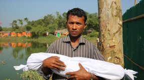 En man håller sin döda son som är insvept i ett vitt skynke