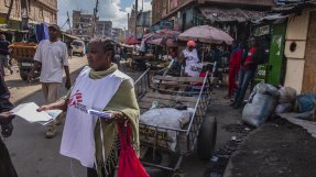 Hälsoinformatören Catherine Ndunge delar ut flyers om kliniken på en av Mathares myllrande gator. 