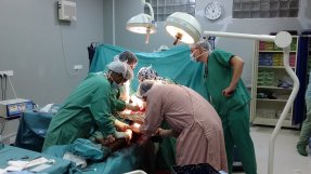 En operation i en operationssal med fem personer och en patient i