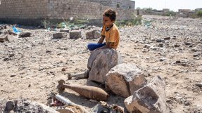 Ett barn sitter på en sten bredvid tomma raketer