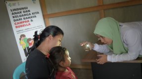 En läkare lyser med en mobillampa i ögonen på ett ungt barn
