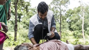 En läkare tar pulsen på en patient på marken