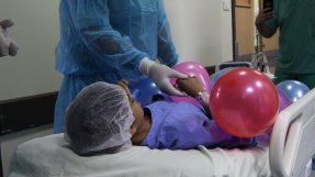 Salwa ligger på en bår med ballonger på sig