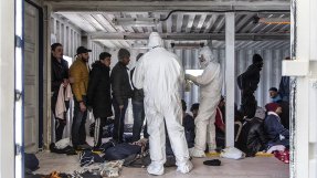 Två personer i skyddsdräkt kontrollerar migranter ombord Ocean Viking