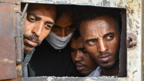 Fyra män tittar ut från ett förvar i Libyen.