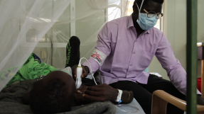 En man i munskydd behandlar en patient med tuberkulos