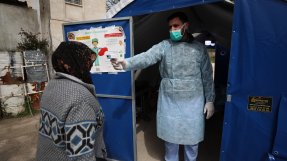 En man håller en termometer mot pannan på en kvinna