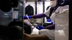 En kvinna gör ett ultraljud på en gravid kvinna som ligger på en bår i en ambulans.