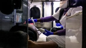 En kvinna gör ett ultraljud på en gravid kvinna som ligger på en bår i en ambulans.