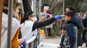 Medicinsk personal tar temperaturen på ett barn i flyktinglägret Moria, på den grekiska ön Lesbos.