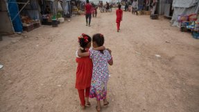 Foto av två barn håller om varandra och går läng en väg.