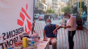 En man sitter på en stol och får vård vid en mobil klinik efter explosionen i Beirut, Libanon.