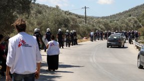 Personal från Läkare Utan Gränser tittar på när polisen för bort demonstranter utanför Moria, på den grekiska ön Lesbos.