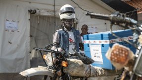En man står vid en motorcykel vid en vaccinationskampanj mot mässling i Kongo-Kinshasa.