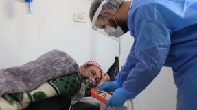 En sjuksköterska tittar till en patient med misstänkt covid-19 på sjukhuset i Idlib, Syrien.