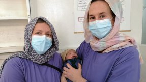 Barnmorskorna Astrid och Lena håller i en nyfödd bebis, på Khost kvinnorsjukhus i Afganistan.