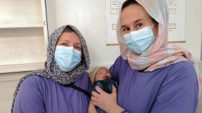 Barnmorskorna Astrid och Lena håller i en nyfödd bebis, på Khost kvinnorsjukhus i Afganistan.