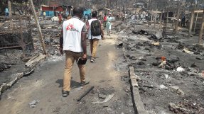 Två personer från Läkare Utan Gränser går genom det nedbrunna lägret i Cox,s Bazar, Bangladesh.