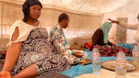 Safi Keita, som är gravid, sitter i ett tält tillsammans med andra kvinnor i Assamaka, Niger.