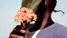 En kvinna i Centralafrikanska republiken håller en blomma framför sitt ansikte.