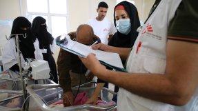 Personal undersöker en bebis under en rond på sjukhuset i al-Qanawis.