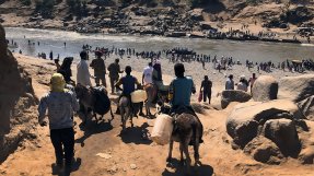 Vid gränsövergången Hamadayet korsar människor från Etiopien en flod i november 2020. Vissa flyr till fots ner mot floden, och andra på åsnor.