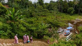 Sjukvårdspersonal går mot en båt i djungeln i Amazonas.