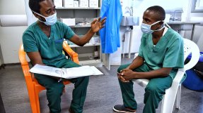 Två sjukhusklädda personer samtalar.