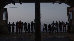 Flera människor står i motljus på däck ombord på sök- och räddningsfartyget Geo Barents och tittar ut mot havet.