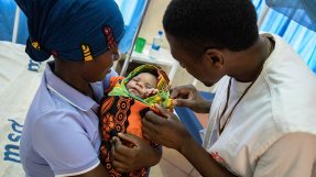 En anställd från Läkare Utan Gränser tittar till en nyfödd pojke på sjukhuset i Nduta flyktingläger i Tanzania. Pojken är invirad i en filt och hans mamma håller hon tätt intill sig.