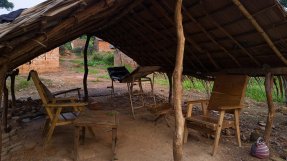 Två övergivna stolar och en gammal brits under en halmtak i Nzako, Centralafrikanska republiken.