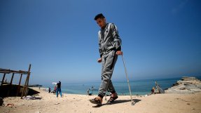 En ung man går på kryckor på en strand i Gaza, Palestina.