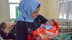 Barnläkaren Mónica Costeira, som arbetar på vårt sjukhus i al-Qanawis, Jemen, håller en liten bebis i famnen och ler.