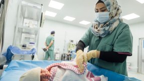 En nyfödd bebis på Nablus sjukhus i västa Mosul, Irak, sveps in i en filt av en sjukvårdspersonal.