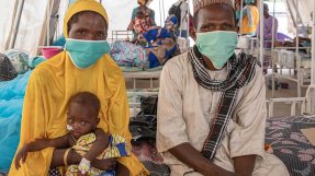 Ali, som vårdas på sjukhuset  i Magaria i Niger för malaria och uttorkning, sitter i sin mammas knä på en säng.