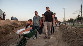 En man som korsar gränsen till Grekland utan sin rullstol. Därför måste hans  vänner dra honom i en skottkärra