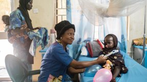 Yaashe och hennes mamma sitter på en säng på Noma-sjukhuset i Sokoto, Nigeria.