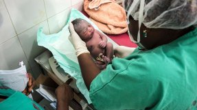 En nyfödd bebis ligger i händerna på sjukvårdspersonal på Läkare Utan Gränsers mödravårds- och förlossningsklinik  i Jahun, norra Nigeria.