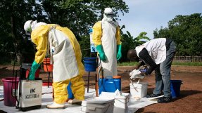 Teamledaren Gilkenny Okonkwo i delstaten Ebonyi i sydöstra Nigeria ser till att skyddsutrustningen sitter som den ska på två kollegor inför saneringen av ett hus där lassaviruset upptäckts.