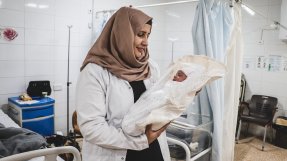Rahma Adla Abdallah, en av de ansvariga barnmorskorna på mödravårdsmottagningen al-Amal i Mosul, Irak, håller om nyfödda Rivan.