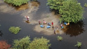 En grupp människor i ett översvämmat landskap. 