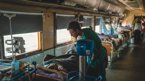 Sjuksköterskan Dmytro Mohylnytskyi tittar till en patient ombord på Läkare Utan Gränsers medicinska tåg i Ukraina.