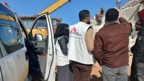 Två personer med Läkare Utan Gränser västar står och kollar på rasmassorna efter jordskalvet som drabbade Syrien och Turkiet.
